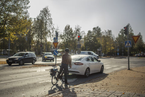 auto ja pyöräilijä pysähtyneenä punaisiin liikennevaloihin risteyksessä.