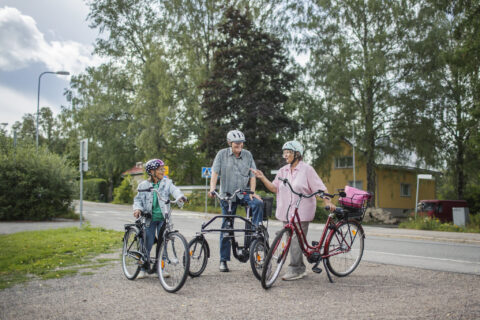 Kolme pyöräilijää pysähtyneenä tien poskeen juttelemaan.